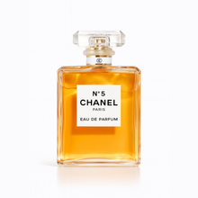 Chanel No. 5 Eau de Parfum by Chanel transparent glass bottle with golden fragrance on a white background