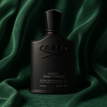 Creed Green Irish Tweed matte black perfume bottle displayed against luxurious green fabric backdrop