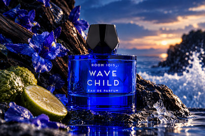 Room 1015 Wavechild Eau de Parfum unisex fragrance bottle in vibrant cobalt blue glass with black geometric cap, surrounded by blue flowers, citrus fruit and ocean waves at sunset