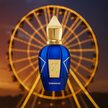 Xerjoff Torino 23 bottle in front of a golden Ferris wheel at sunset, luxury niche perfume presentation